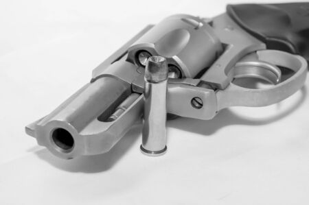 A loaded 357 stainless steel revolver with a hollow point bullet next to it shot in black and whiteの写真素材