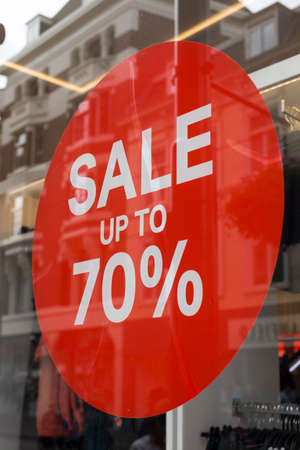 Sale up to 70 percent red sign. Red circle with sale up to seventy percent inscription sticked on the store windowの写真素材