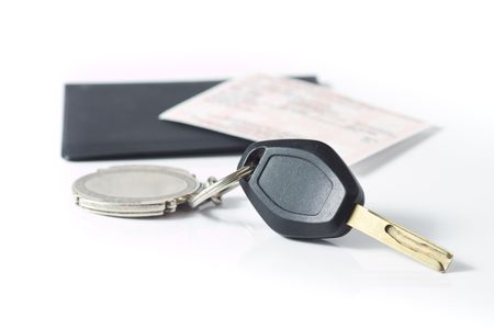 Car keys attached to a keychain, with an insurance slip on top of a black protector in behind, isolated on white.の写真素材