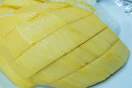 closeup of bright mango with sticky rice and silver spoon on wooden tableの写真素材