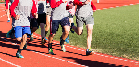 Group of high school boys running fast on a red track while wearing spikesの写真素材