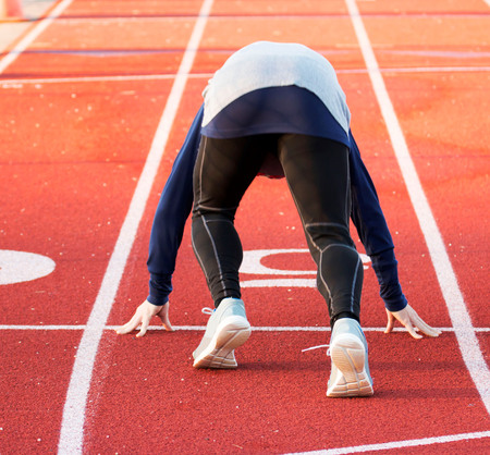 A sprinter training for the 100 mete dash on a high school track in the winterの写真素材