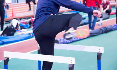 An athlete warms up for their race doing hurdle drills on the infield of an indoor track and field arenaの写真素材