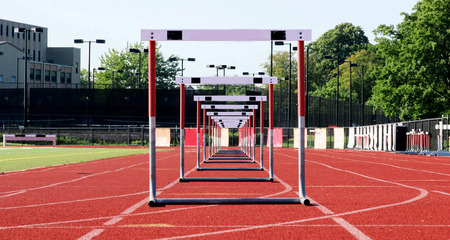 One lane of hurdles lined up for racing on a red track.の写真素材
