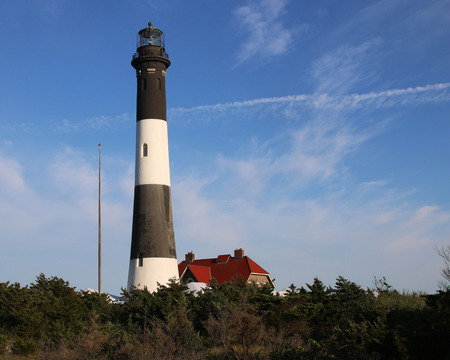 Fire Island Lighthouse with a deep blue sky and some light clouds behind it.の写真素材