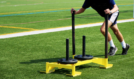 Athlete pushing a weighted sled for speed trainingの写真素材