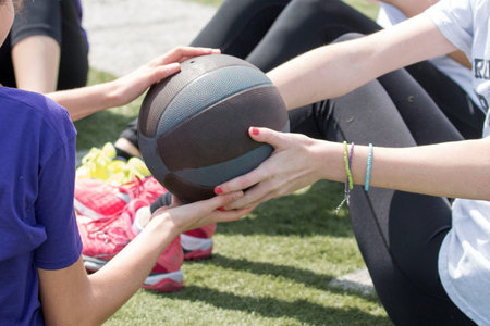 High school girls pass a medicine ball by twisting to the side, in a groupの写真素材