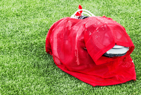 A red practice uniform over full pads is ready to be put on by a high school football player for practice.の写真素材