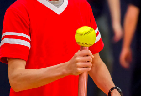 A high school athlete is balancing a softball on a baton for a fun relay race.
