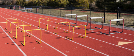 Low yellow hurdles and normal hurdles are set up on a red track for athletes to jump over during speed and jumping practice.の写真素材