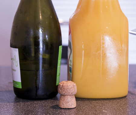 A bottle of champagne and a bottle of orange juice on a table with a cork.の写真素材