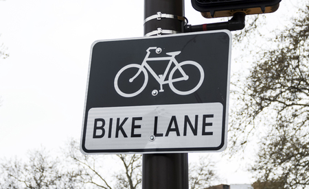 A black and white sign is on a black pole marking a bike lane.の写真素材