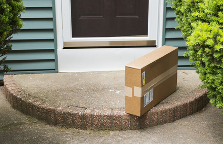 A brown cardboard box is left on the front stoop after being delivered while no one was home.の写真素材