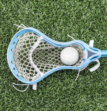 A lacrosse stick with a ball in it laying on the turf.の写真素材