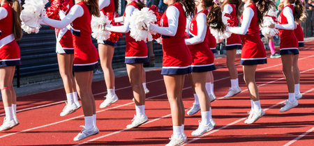 A group of high school cheeleaders are motivating the fans by cheering during a football game.