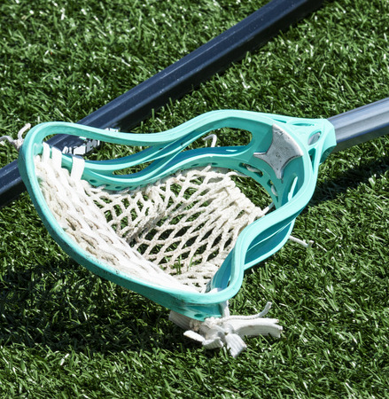 A high school boys aqua blue lacrosse stick lying on the ground.の写真素材