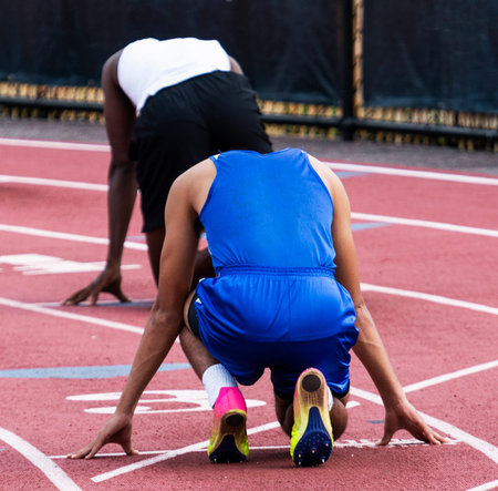 Two male high school sprinters are ready to sprint in lanes three and four during a track and field...