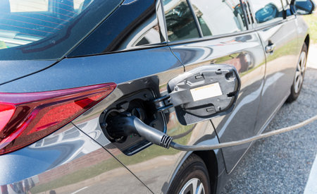 A gray electric hybrid car is shown plugged in for charging.