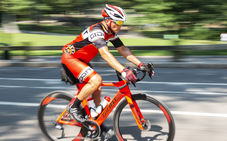 New York City, USA - 15 August 2018: A man is training on a road racing bike in central park with the background blurred and wheels look like they are moving.のeditorial素材