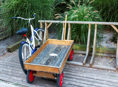 A cruiser bicycle and a wooden wagan are parked in a wooden bike rack in front of a summer home in...