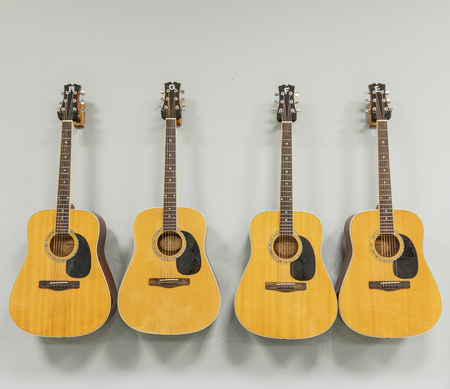 Four acoustic guitars are hung next to each other on a white wall.の写真素材