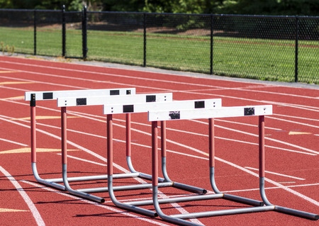 Four hurdles are together on a red track for athletes to do form and agility drills with.の写真素材