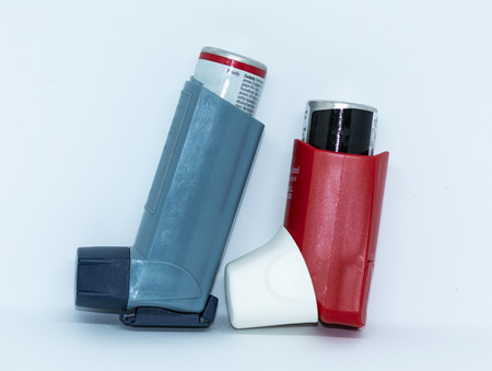 One blue and one red athma rescue inhaler standing up with a white background.の写真素材