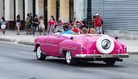 Havana, Cuba - 25 July 2018: A family is being chauffered aound in a beautiful vintage pink Chevrolet convertible through the city of Havana Cuba.のeditorial素材