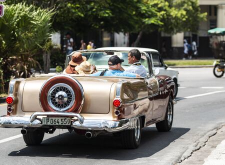 Havana, Cuba - 25 July 2018: Tourist being driven around Havana Cuba in a vintage 1950's gold convertible.のeditorial素材