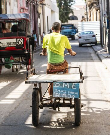 Havana, Cuba - 25 July 2018: A cuban man riding a tricycle modified into a work cart through the street in old Havana City Cuba.のeditorial素材