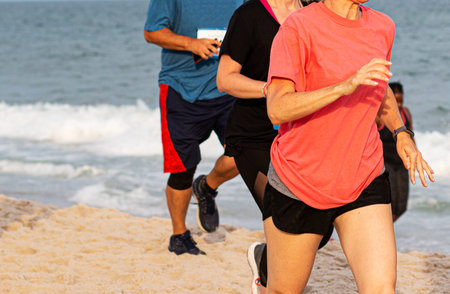 People running of the sand by the ocean on a beach on Long Island.