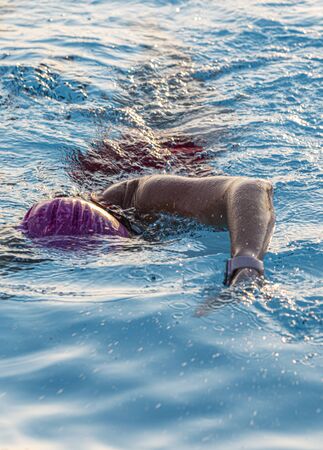 Front view of a close up of a female swimmer swimming in an aqua blue outdoor pool.の写真素材