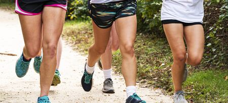 A group of high school girls are running on a dirt path in a local park during cross countyr practice.の写真素材