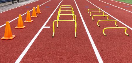 Cones and mini hurdles set up in lanes on a track for speed and agility practice.の写真素材