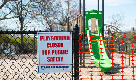 Playground closed for public safety sign posted on the fence of a play area in Babylon Village New...