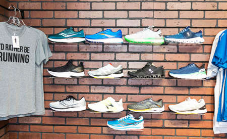 Smithtown, New York, USA - 28 August 2020: The wall of a running shoe specialty store has different brands of shoes displayed on the wall next to some t-shirts.のeditorial素材