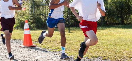 Three high school boys racing on gravel during a cross country race close to the finish.
