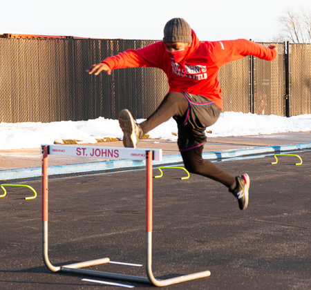 West Islip, New York, USA - 5 February 2021: A runner running over a hurdle in a parking lot because...