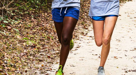 Frint view of two girls running on a dirt path in a park wearing shorts,の写真素材