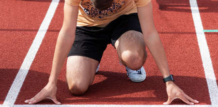 Front view of a high school sprinter at the starting line ready to practice running a sprint in lanes at practice.の写真素材
