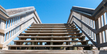 Wood stairs with wood railing over sand dunes on Fire Island looking up at a deep blue sky above.