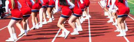 High school cheelearders dancing on the track perfoming for the fans at a football game.
