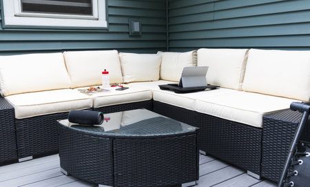 A backyard decks wicker coach set up to work on from home with a computer, phone water bottle and speaker for music.の写真素材