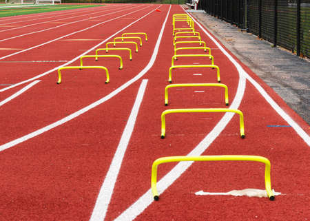 Two lanes of small yellow mini banana hurdels are set up on a track for sprint runners to run over performing the wicket drill to learn speed progression.の写真素材