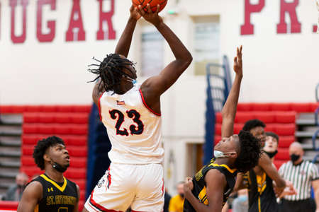 West Islip, New York, USA - 21 January 2022: High school basketball player shooting the ball above the defenders wearing facemasks under their chins due to COVID-19 coronavirus pandemic rules in 2022.のeditorial素材