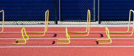 Small and larger yellow plasic hurdles in lanes on a track for speed and agility practice.の写真素材