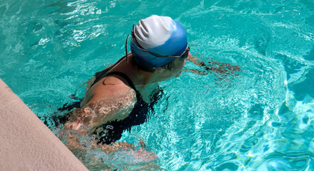Close up of a female swimmer pushing off of the wall of an outdoor hotel pool between laps.