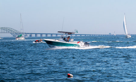 Babylon,  New York, USA - 25 June 2022: Motor boats, sailboats and waverunners moving fast in the great south bay with the bridge in view.のeditorial素材