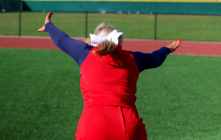 Cheerleader practicing running to do flips on a green turf fieldの写真素材