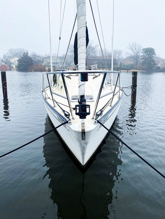 A vertical veiw of one  sailboat s tied to a dock and moored in the water in Babylon Village.
